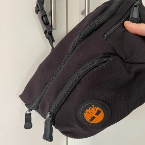 Midjeväska - Från Timberland. Inköpt second hand. Har 5 fack och ett fack på insidan. Jättebra skick! 