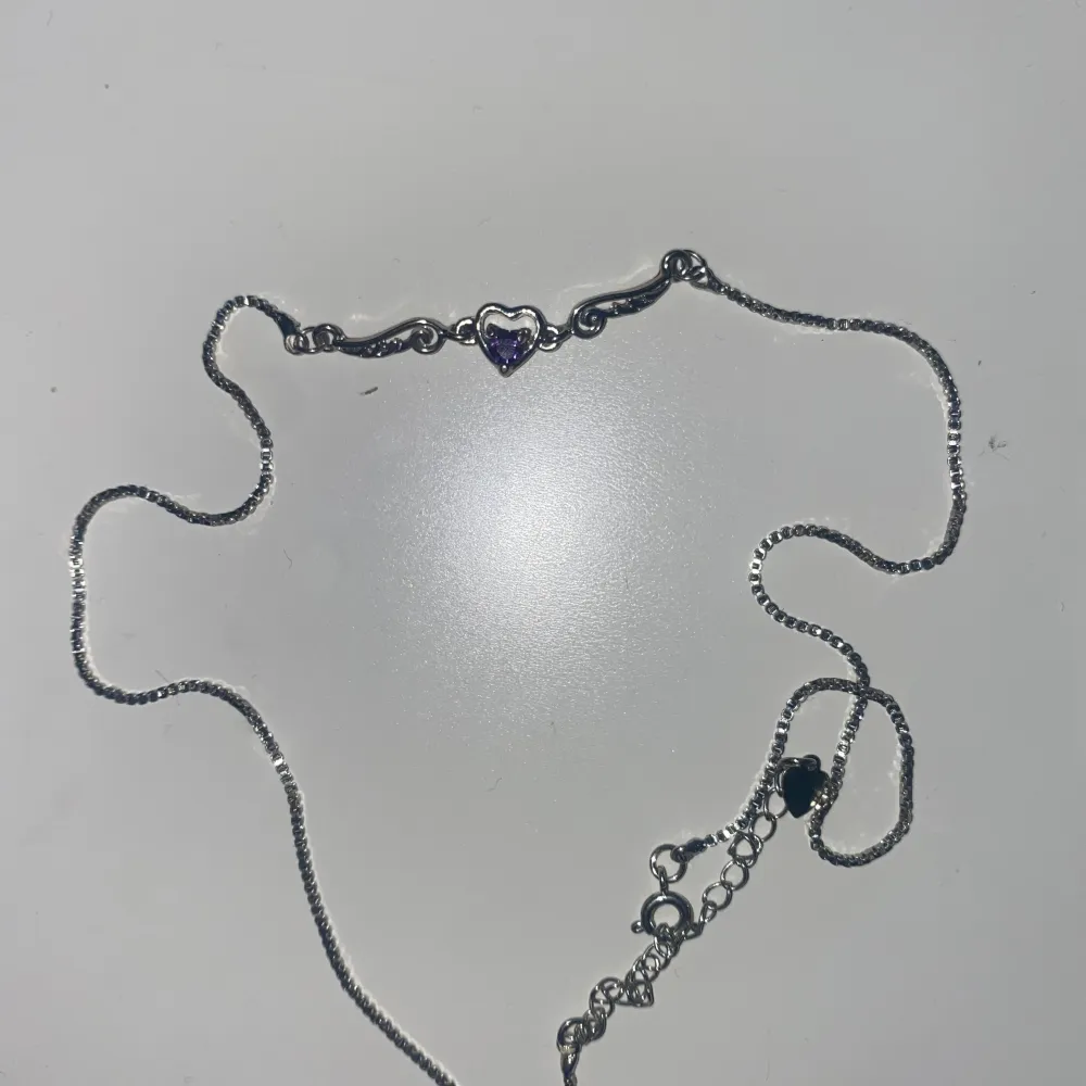 Silverfärgat halsband med lila hjärta i mitten. Accessoarer.