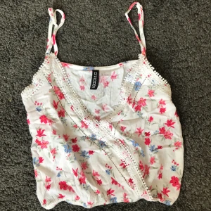 Blommig topp - Helt oanvänd topp köpt på HM för två år sedan. Kort och tunn, perfekt till sommaren💚 storlek 32 men passar även 34. Banden får att justera💚