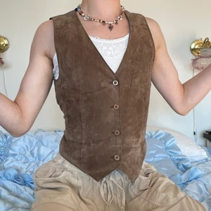 Kostymväst brun mocka rosett vintage - Brun vintage mocka kostymväst med snörning i ryggen och det fetaste mönstret som avbildar fåglar 🎞 Denna toppen är justerbar i ryggen så att den ska passa precis som önskas och dessutom är mönstret på ryggens tyg såå fint! Skärningen på hela västen är helt underbar och är i helhet så skön! Passar perfekt med ett linne med spets nu till sommaren eller med en skjorta under för en mer festlig look! :D