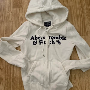 ABERCROMBIE&FITCH - Vit zip-hoodie från Abercrombie & Fitch i strl. XS. Köpt i USA men blev tyvärr för liten så hann inte användas mycket. Eventuell frakt betalas av köparen! Har även liknande från Hollister i olika färger vid intresse! 
