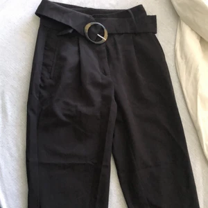 NAKD byxor  - Kostym byxor i ”paperbag” form från NAKD i storlek 38. Sitter tightare i midjan och låren, men lösare vid vaderna, går att justera med det tillhörande bältet. Byxorna är i nyskick och har endast använts fåtal gånger. Nypris 599.