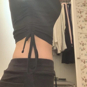 Svart topp  - Svart T-shirt med ”knytning” vid midjan på båda sidorna. Jättefin och bra skick även om den är använd några gånger. Man kan justera själv hur kort man vill att den ska vara med hjälp av knytningarna på sidorna.