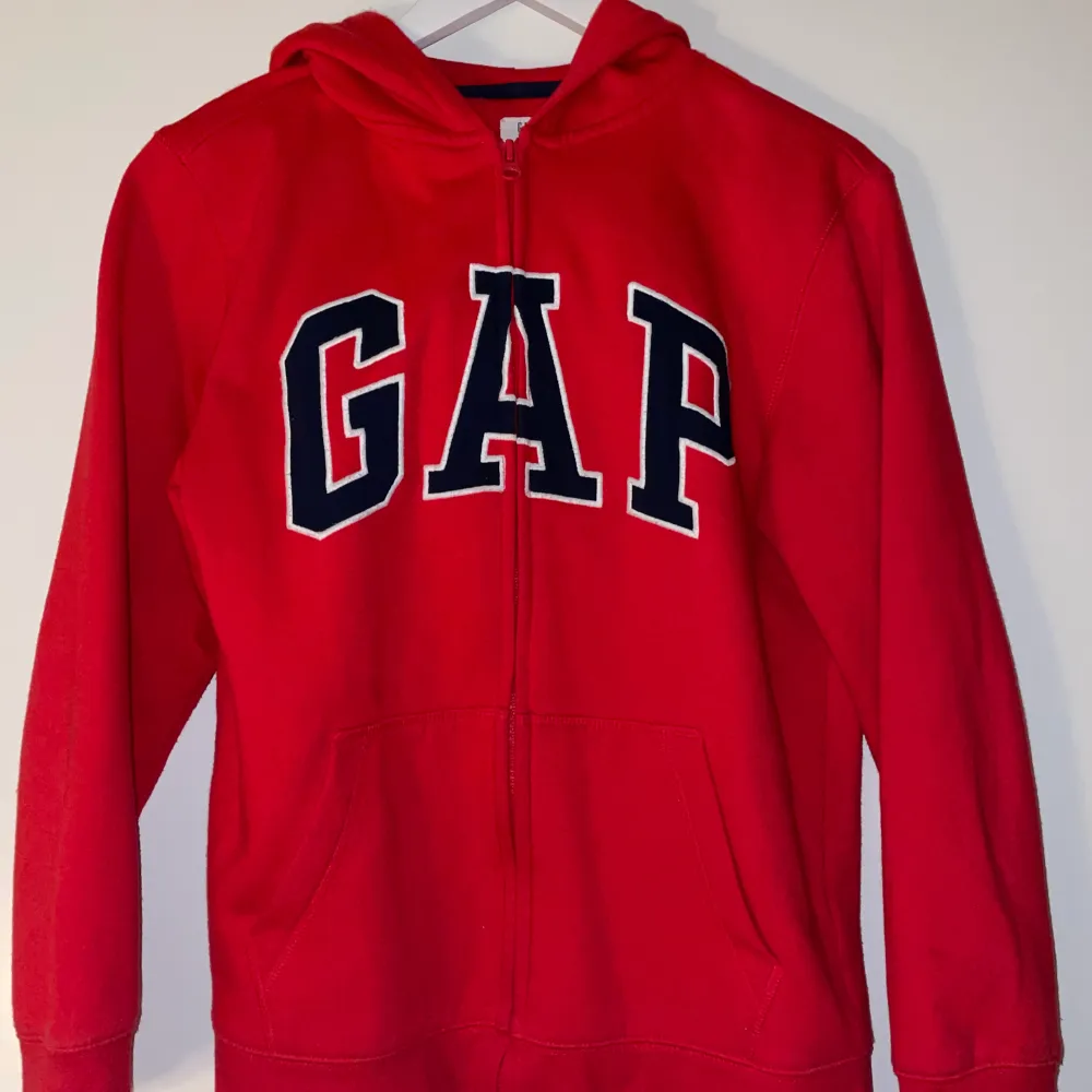 En röd zip up hoodie från GAP. Den är i barnstorlek xxl, men skulle säga att den även har passformen S i vanlig storlek. Den är även i mycket fint skick!!. Hoodies.