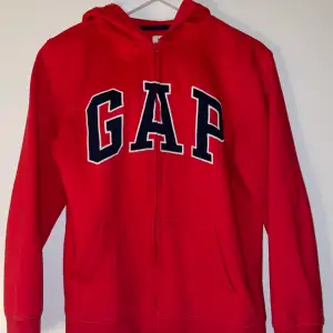 En röd zip up hoodie från GAP. Den är i barnstorlek xxl, men skulle säga att den även har passformen S i vanlig storlek. Den är även i mycket fint skick!!