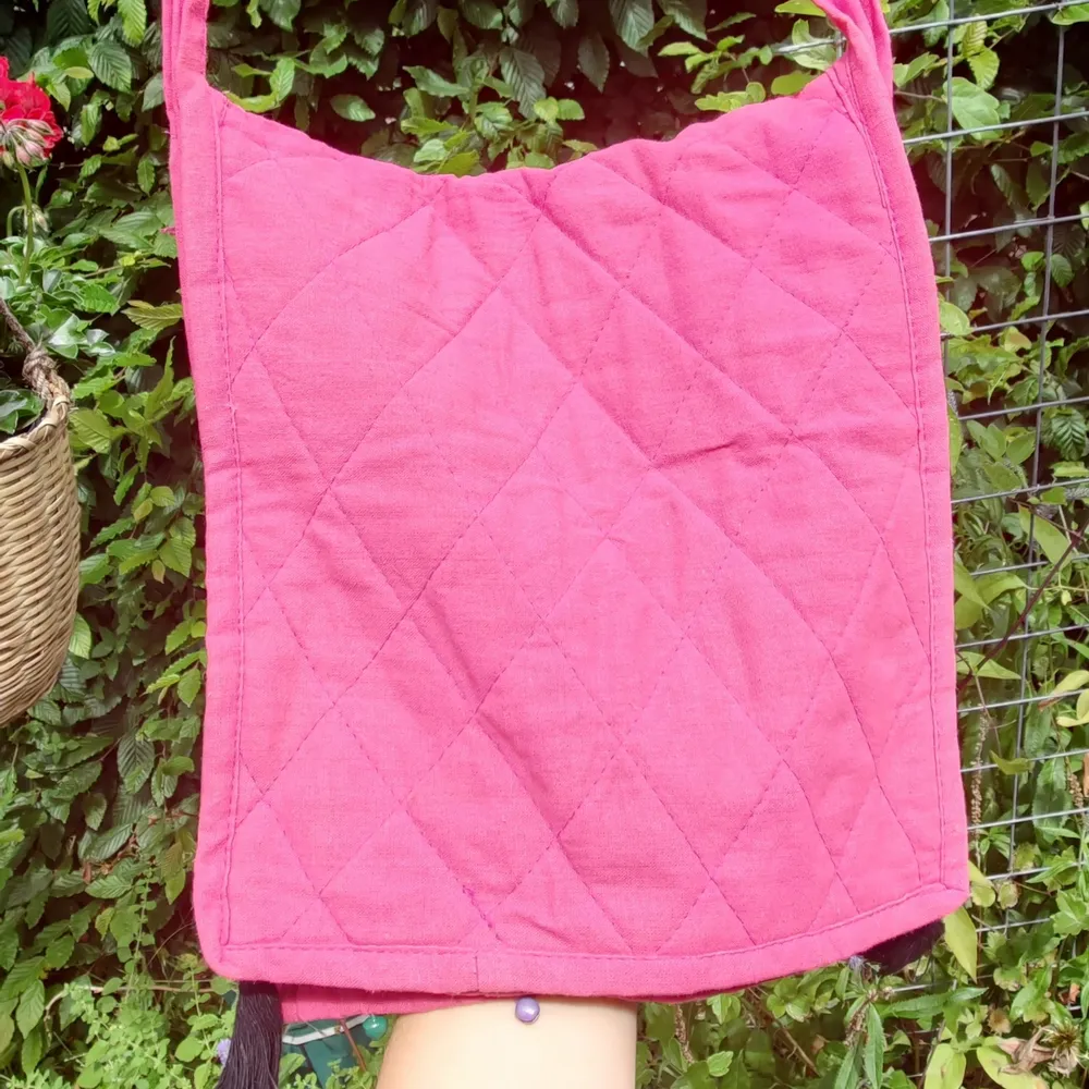 Fin rosa väska med orientaliskt tema. Den har bjällror längsmed nederkanten och två tofsar i vardera hörn.  Kan både skicka spårbart och icke spårbart.. Väskor.