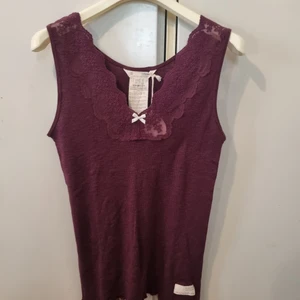 Odd Molly rib-eye tank linne storlek 4 - Helt ny med tags! Nypris 595kr.  Du budar på en rib-eye tank top i en vacker, diskret melerad vinröd (burgundy) färg från Odd Molly. Ett perfekt baslinne som passar i alla lägen! Ärmlös modell i mjuk ribbstickning med fin spetsinfällning fram i halsen.