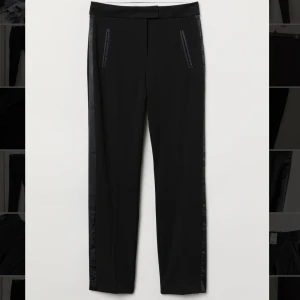 Byxor - Ett par slacks/kostymbyxa i storlek 36. Stretchig, vävd kvalitet. Byxorna har sidfickor och avsmalnande ben. Normalhög midja stängs med dold hyska och hake. Aldrig använda, lappen kvar. 