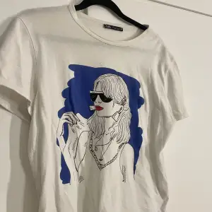 Säljer denna snygga T-shirt från zara med tryck på framsidan. Inga defekter finns förutom ett litet litet hål som inte ens syns, som ni kan se på bilden på trycket. Storlek L men passar mig som är S/M🫶🏻