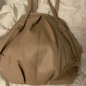 Beige/rosa väska -  en medelstor väska med ett justerbarband och ett med färdig storlek. Ett inne fack och mycket plats inuti .