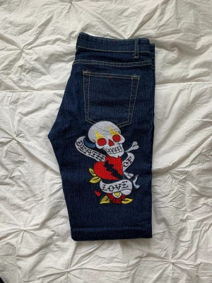 Blåa jeans - Lågmidjade blåa jeans med döskallar och annat tryck på rumpan och längst ner på ena benet.  Dem är ganska tunna och  skinnyjeans🤍