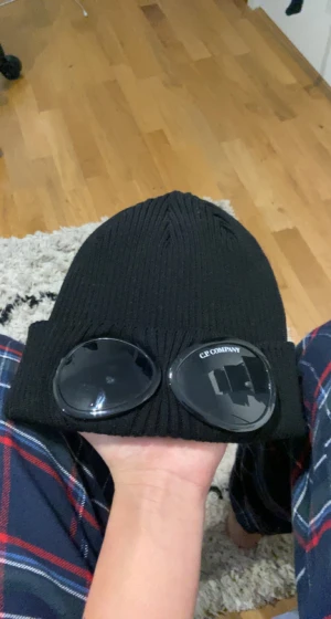 Svart CP Company mössa - Hej! Säljer nu min svarta CP Company mössa. Köpte mössan för cirka ett år sedan för runt omkring 900kr. Mössan kostar i dagsläget 1200kr ny och jag säljer min för 700kr Mössan är i väldigt bra skick. Inga fläckar eller liknande