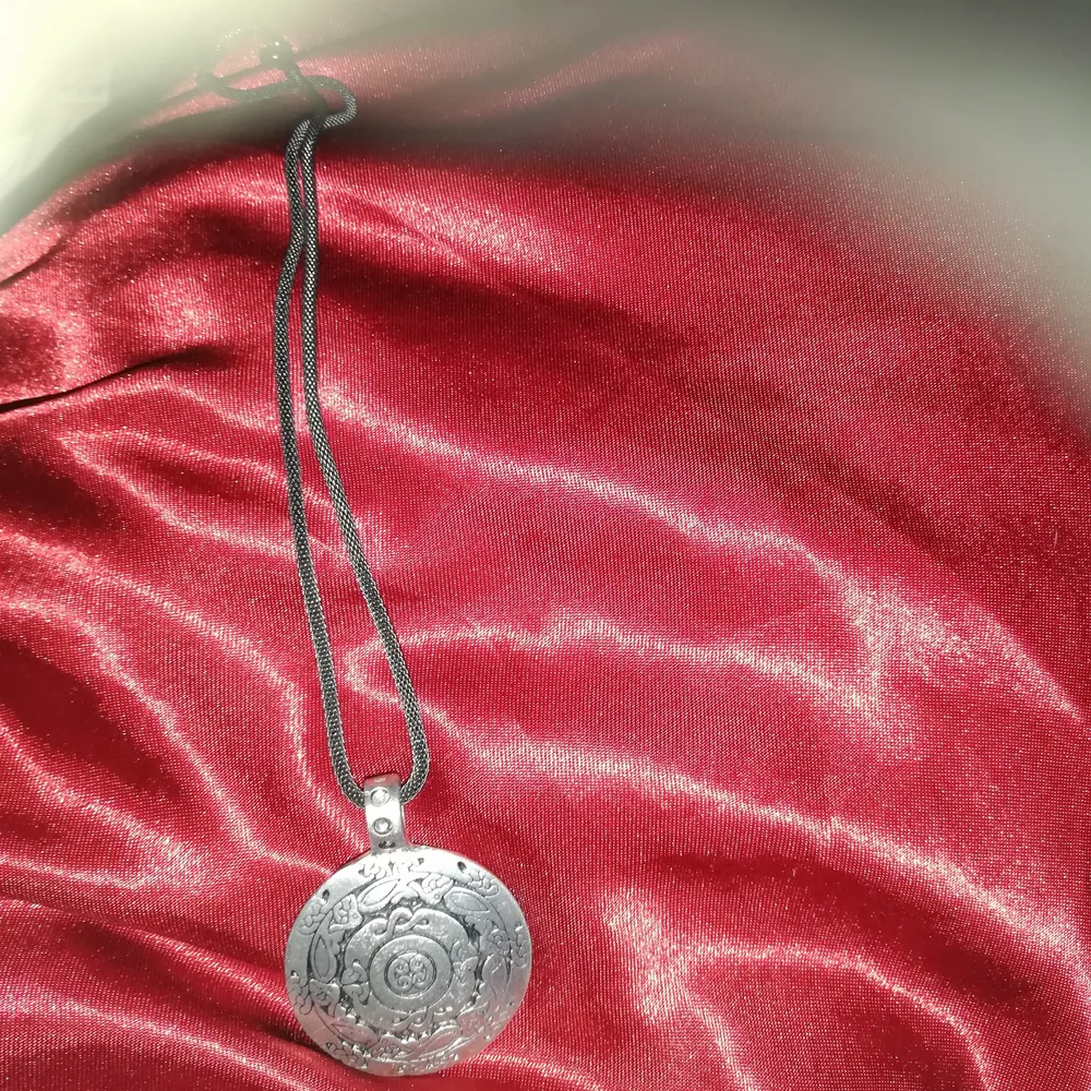 Halsband från vikigmarknad med svart kedja medaljongenn är gjord i tenn o mönstrad använd 1 gång pris 60kr frakt till komer. Accessoarer.