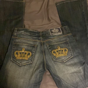 Victoria beckham jeans - Blåa lågmidjade bootcut Victoria beckhamn jeans,med Guldiga kroner. Bra skick. Storlek 28, midje måtet är 74 cm och innerbenet är 80 cm. 🥰