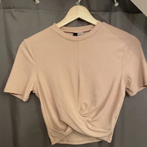Knuten t-shirt i beige-rosa  - Söt topp som jag köpte på H&M för något år sedan. Har använt 1 gång. Säljer den för att jag vuxit ur denne 🥰🥰 Köpte den för 129kr men säljer för 50❤️