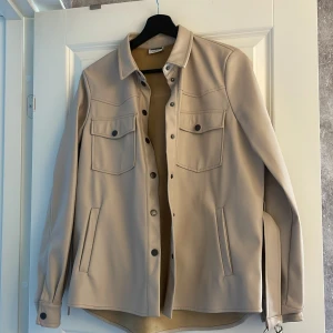 Skinnskjorta - Snygg skjorta/jacka i fake skinn. Säljer då jag aldrig använder den. Storlek S. Beige 