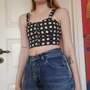 Bommig crop top - Blommigt croppat linne med hängslen och knappar. Passar bra att ha som den är eller med en tröja under!