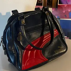 En jättefin handväska från puma. Den är mörkblå och röd.