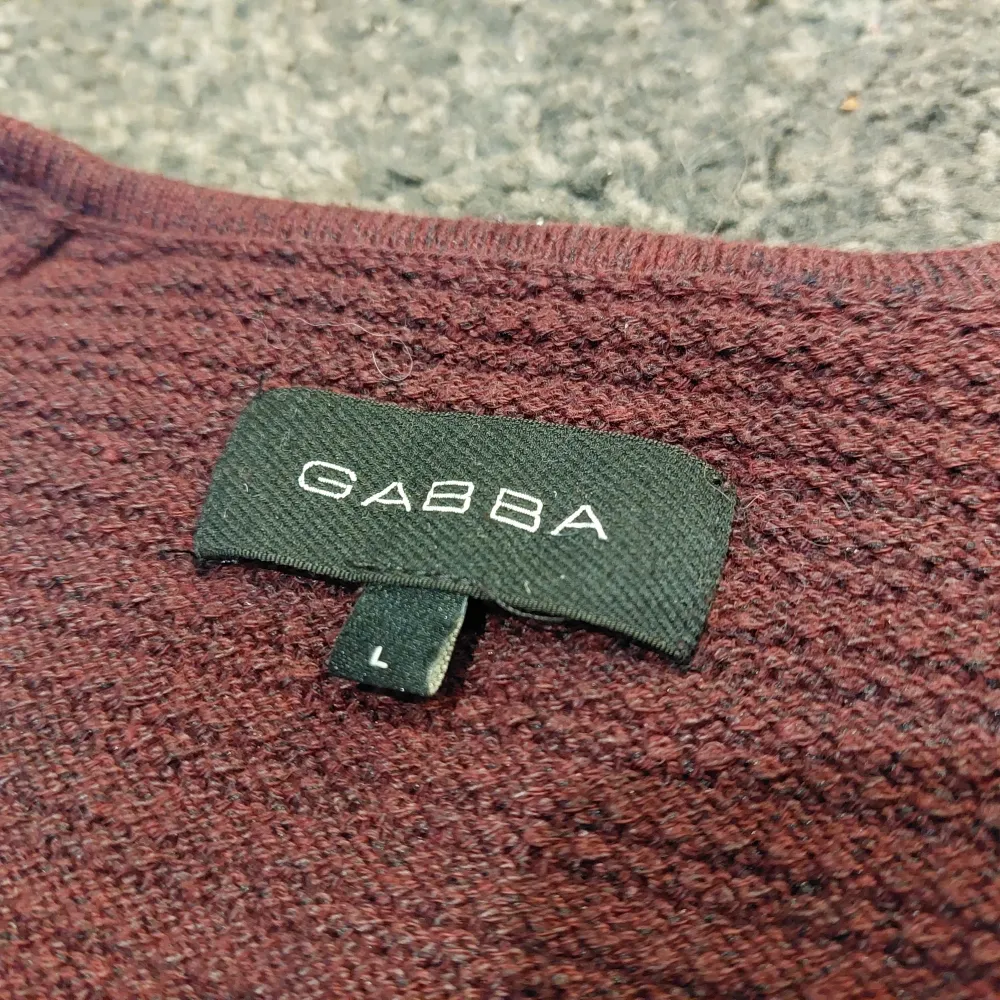 Vinröd stickad tröja från GABBA.  Ny pris 900kr En sömm på högra sidan av kragen är sliten men det går nog att fixa väldigt enkelt. Inget motiv.. Stickat.