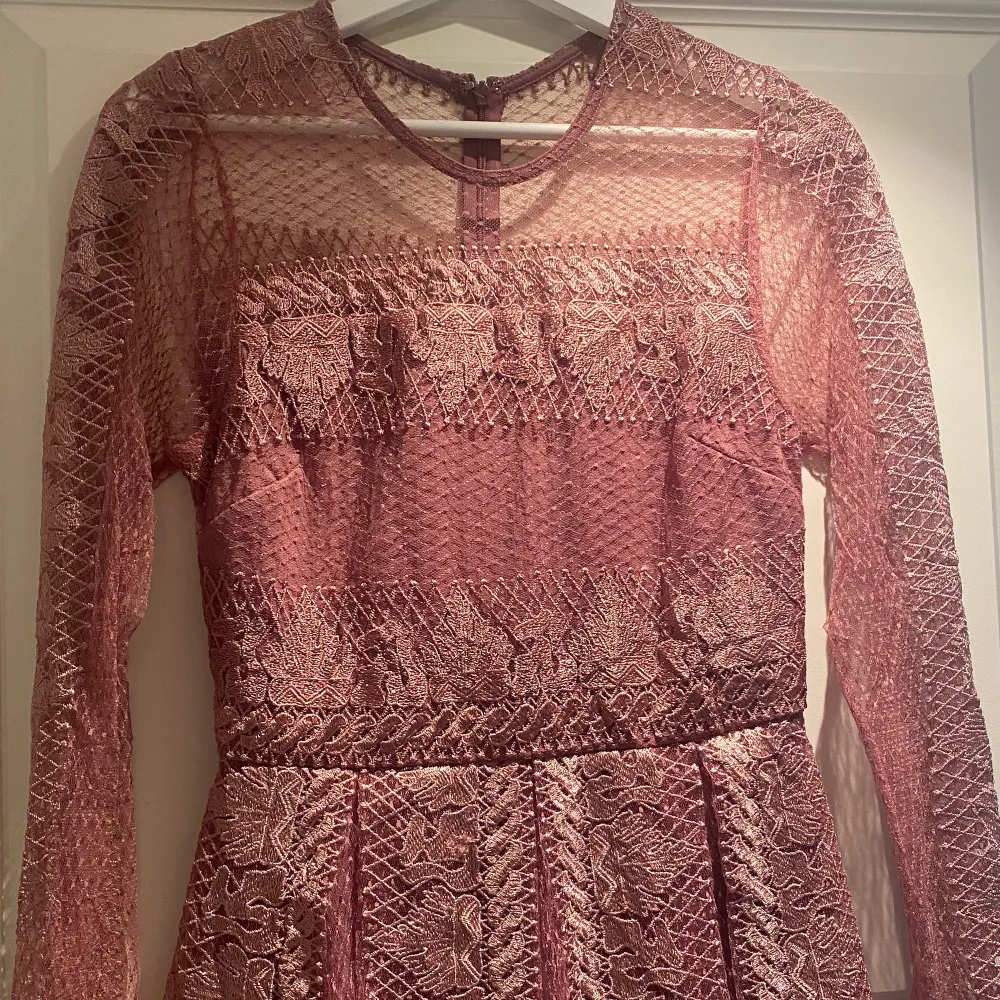 En rosa/lila långärmad klänning med ett fint mönster över hela klänningen. Den är endast använd 1 gång och är som ny. Klänningen är k storlek 36 med en bra passform. Pris kan diskuteras. . Klänningar.