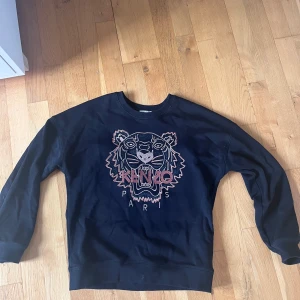 Kenzo tröja - Säljer min kenzotröja i kids-storlek 14A. Tröjan är i gott skick och använt endast ett fåtal gånger! Bakgrundsfärgen är svart. Perfekt till dig som är lite yngre, har mindre storlek eller föredrar en lite mer åtsittande passform! 
