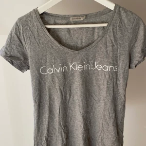 Calvin Klein t-shirt - V-ringad t-shirt med tryck från Calvin Klein i storlek m men passar även XS/S om man vill ha en mer oversize fit. Använd väldigt sparsamt så tröjan är i mycket gott skick. Nypris ca 500 kr