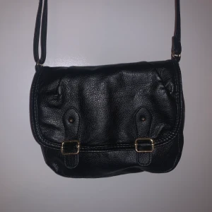 Svart väska  - Axelremsväska med fina gulddetaljer och fakeläder, köpte den här på Plick med kommer inte till användning 💕 axelremmen går att justera! 