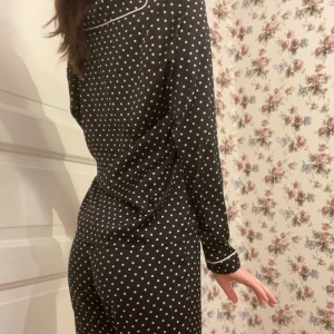 Svart satin pyjamas - Säljer mitt jättesköna satin pyjamas set med vita prickar på! Använder inte längre, men är i toppskick. Byxorna är vida och lite för korta på mig som är 166. Kom gärna privat för fler bilder eller frågor osv så svarar jag så snabbt jag kan!☺️