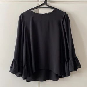 Svart Blus Zara - Svart blus från Zara som inte kommer till användning längre. Vida ärmar med volang. Sparsamt använd 🥰 