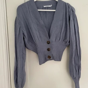 Blå tröja nakd - En blå stickad tröja med åtdragning i midjan. Hela tröjan är väldigt stretchiga. Puffärmars och större ribbstickad. Använd fåtal gånger