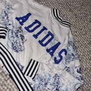 Adidas jacka  - I nyskick, strl S / 38, super fin jacka/ tröja med unikt tryck & design från adidas, inköpt på Junkyard. Kan mötas upp i centrala Stockholm eller skicka om köparen betalar frakt. 