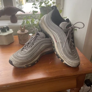 Nike Air Max 97 ”Silver Bullet” - Silver Bullet AM 97:or från 2017 i helt ok skick, mycket liv kvar dock! 3M som lyser när man tar bild med blixt! Skulle bli superfräscha av en städning. Passar som en sz 40,5 snarare än 41. Inköpta på sns. Frakt kan diskuteras i dm!