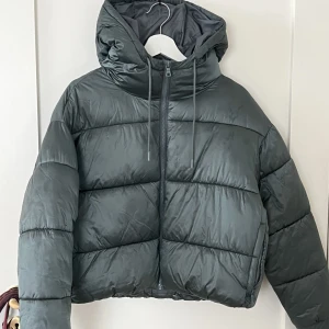 Pufferjacka - Säljer denna grå/gröna pufferjacka som jag köpte på Monki för två år sedan. Har dock inte användnt den sedan 2020.