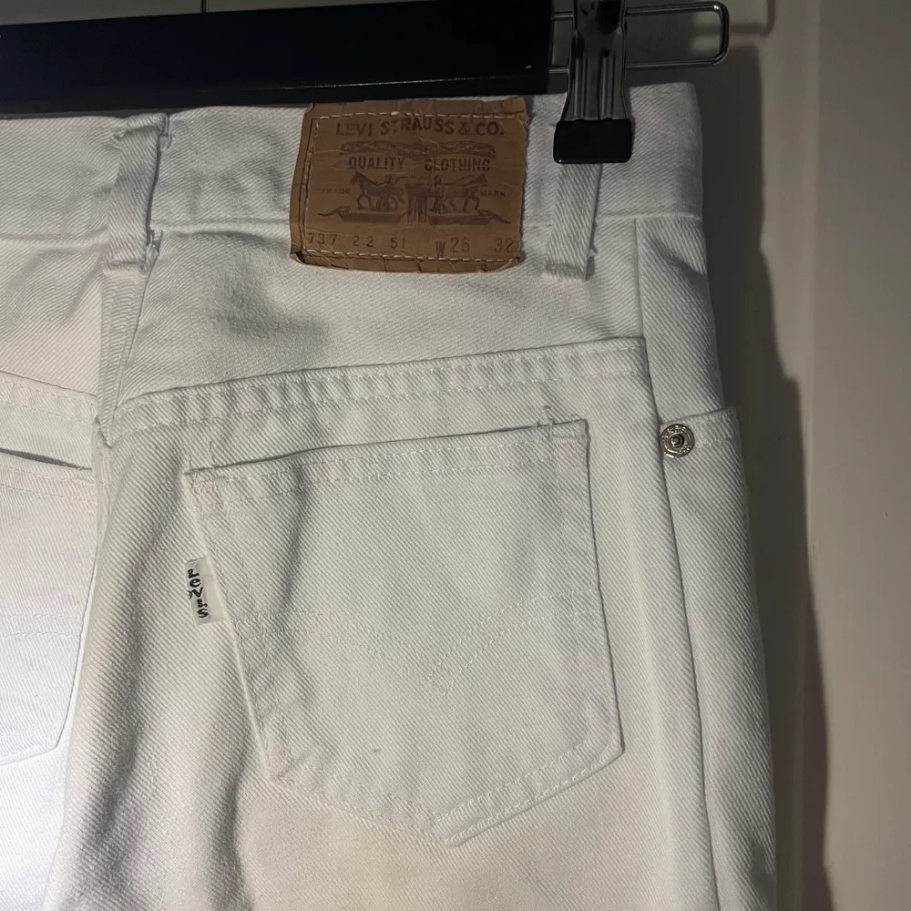 Vita högmidjade jeans m. breda ben. Med Levi’s-ettikett bak, kan ej garantera att de är äkta.  Köpta 2nd hand, i gott skick. Har själv ofta strl 36 i byxor & de är för tighta på mig. Strl W26 L32 enligt byxan, mitt mått blir 74cm innersöm & 30cm bredd.. Jeans & Byxor.