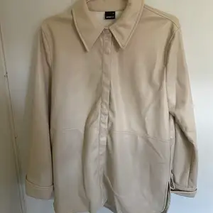 En ljus beige ”läder” skjorta från ginatricot. Köpte den för ungefär 1 år sedan och har knappt använt den. 