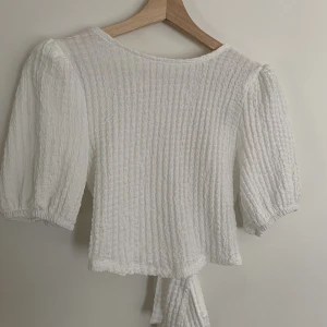 Croptop blus - Säljer min vita croptop blus från ginatricot! Jag är vanligtvis en M och blusen är stretchiga med en super fin öppen rygg som knyts där bak!!! Bara att skriva om man vill ha fler bilder eller ha någon fråga!! Frakten tillkommer!😇😇