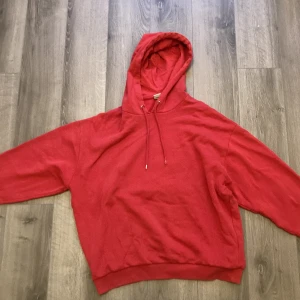 Röd hoodie med tryck  - Jag säljer denna hoodie pågrund av lite användning. Den är i storlek medium och har inget mer fel än att metallen på snörena är lite sönder.
