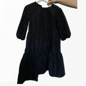 Svart klänning - Fin sparsamt använd klänning från HM. Den är från barnavdelningen i storlek 170 men passar mig som är S-M. Den har 3/4 ärmar och ”volangig” kjol. 