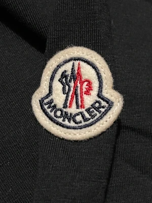 Moncler T-shirt  - Moncler T-shirt, nyskick, svart förg och M i storlek. Den har logon på sidan av ärmen. Bra kvalite och matrial.   Blir glad om du ställer en fråga till mig så in och skriv till mig om du har några funderingar 