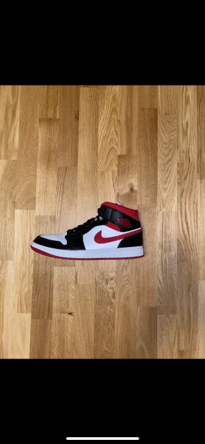 Jordan 1 mid svart/vit/röd - Säljer mina Jordan 1 mids, knappt använda. Köpta för retail: 1300kr på sneakersnstuff. Säljer dem nu för 800kr i skick 9/10, Inga defekter alls. Endast under skon annars som nya! Passar alla mellan 44-45