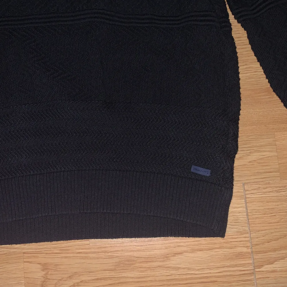 Svart stickad tröja från Gant, med en liten ligga längst ner på tröjan . Tröjor & Koftor.