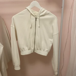 Vit zip up hoodie - Vit zip up hoodie från GinaTricot. Använde en del förut men har inte använts på länge, lite nopprig på insidan men är annars i perfekt skick! Lite oversized och långa i ärmarna vilket är jätteskönt! 