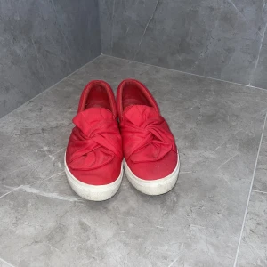Röda Sneakers - Röda sneakers. Detalj: rosett. Skorna är i bra skick. Storlek 38. Säljer dem då dem inte längre kommer till användning.