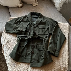 GRÖN OVERSIZED JACKA DAM - Säljer denna snygga gröna höst/vår jackan. Har ett bälte vid midjan. Storlek Xs men passformen är oversized så passar nog upp till liten M. Finns ej att köpa längre. Skicket är nyskick. Säljer för 480 kr. Köparen står för frakten!