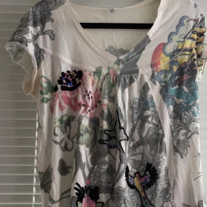 T-Shirt med figurer och stenar på i storlek S - Väldigt fin tröja i unik stil med små sudda figurer som även har små stenar fast på sig. Den är ganska välanvänd tidigare men legat i några år i en garderob, några stenar har lossnat! Den är stor i storlek och sitter ganska löst!  Jag har katt och kanin!