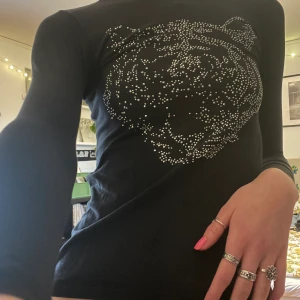 Svart långärmad tröja med rhinestones på - Tight svart långärmad tröja med rhinestones på i mönstret av en tiger. Köpt secondhand på barnavdelningen men väldigt stretchig. Skriv för fler bilder eller frågor 