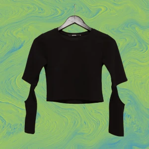 Cut-out crop top - Svart crop top med längre ärmar och cut-outs i ett parti vid armågarna. Storlek S, men sitter som en XS (väldigt tight). Nyskick.
