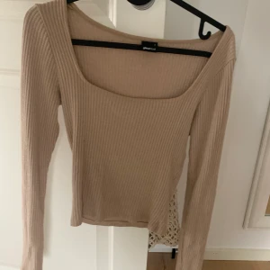 Smickrande topp - En beige tunn, ribbad tröja. Beige med en rak uringning. 