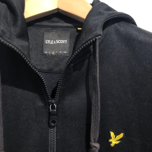 Lyle & Scott Zipup - 58% polyester och 42% cotton lyle and scott zipup köpt på NK. Lite använt men har lite skador kan skicka fler bilder. Storlek M. Längd 60cm. Byst 100cm. Ärmlängd 62cm.