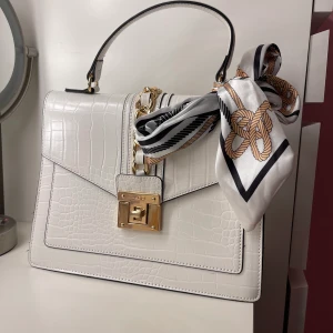 Vit handväska  - Aldrig använd, kommer med en justerbar axelband i samma material som på väskan i färgen vit. 